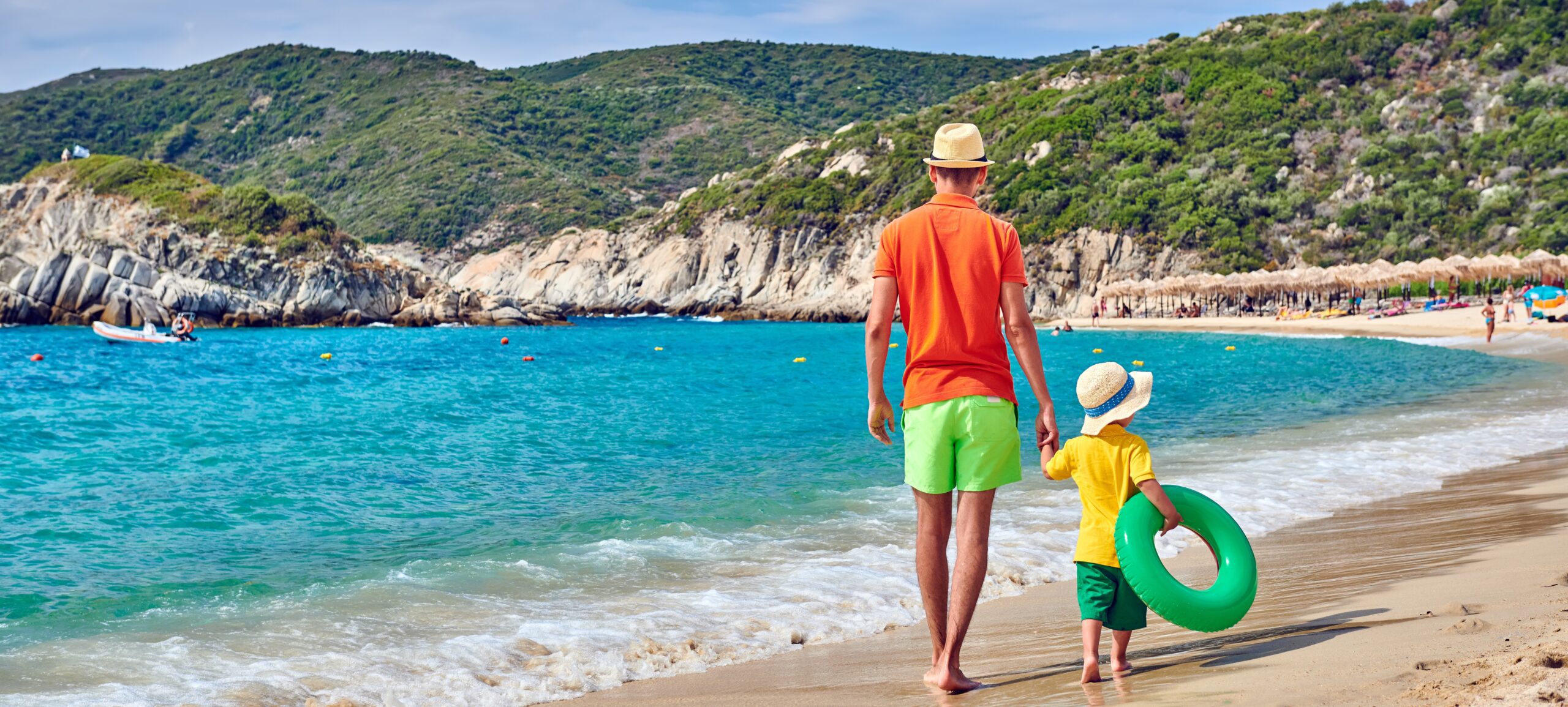 Father and boy walking along a beach in Greece